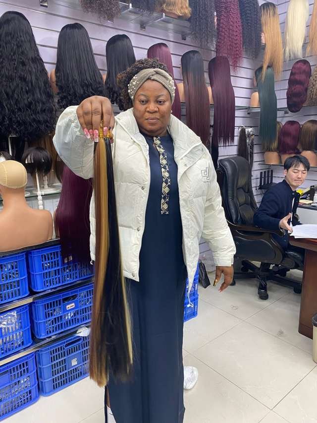 Queen Nkem inspecting hair products at a factory showroom in China