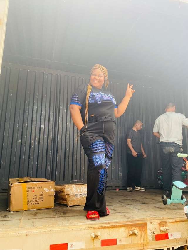 Queen Nkem standing inside a shipping container with workers in China